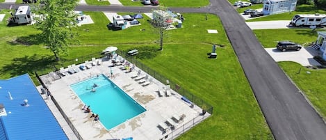 An aerial view of a campground with a swimming pool, RVs, and mobile homes.
