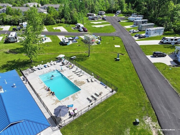 An aerial view of a campground with a swimming pool, RVs, and mobile homes.