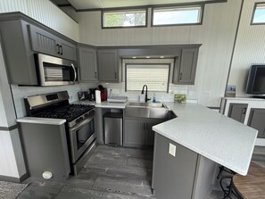 A modern kitchen with grey cabinetry, stainless steel appliances, and a large island with a countertop.