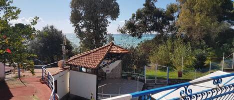 A coastal view with a small building, a fenced area, and a railing.