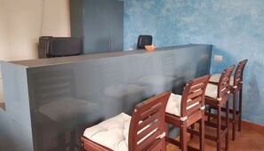 A reception area with a counter, a black office chair, and wooden chairs with cushions. - Villaggio Residence Villamarina (Camerota)