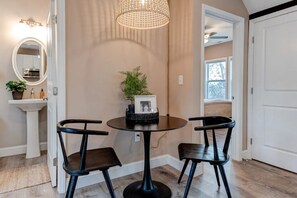 A dining area with a round table, two chairs, a pendant light, a mirror, and a plant on the wall. - Hillside Hideaway Boho 3BR Home w Gameroom, Waffle Bar, Gas Fire Pit, Mtn Views! (Canton)