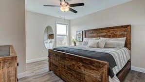 Ein Schlafzimmer mit einem hölzernen Bett, einem Deckenventilator und einem großen Fenster.