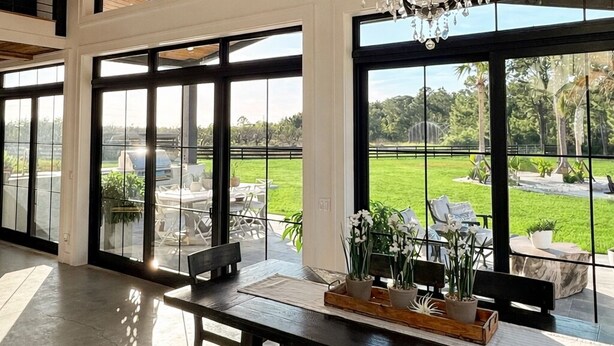 A spacious dining area with large windows, a chandelier, and a view of the outdoors. - Sebring International Races! (Sebring)