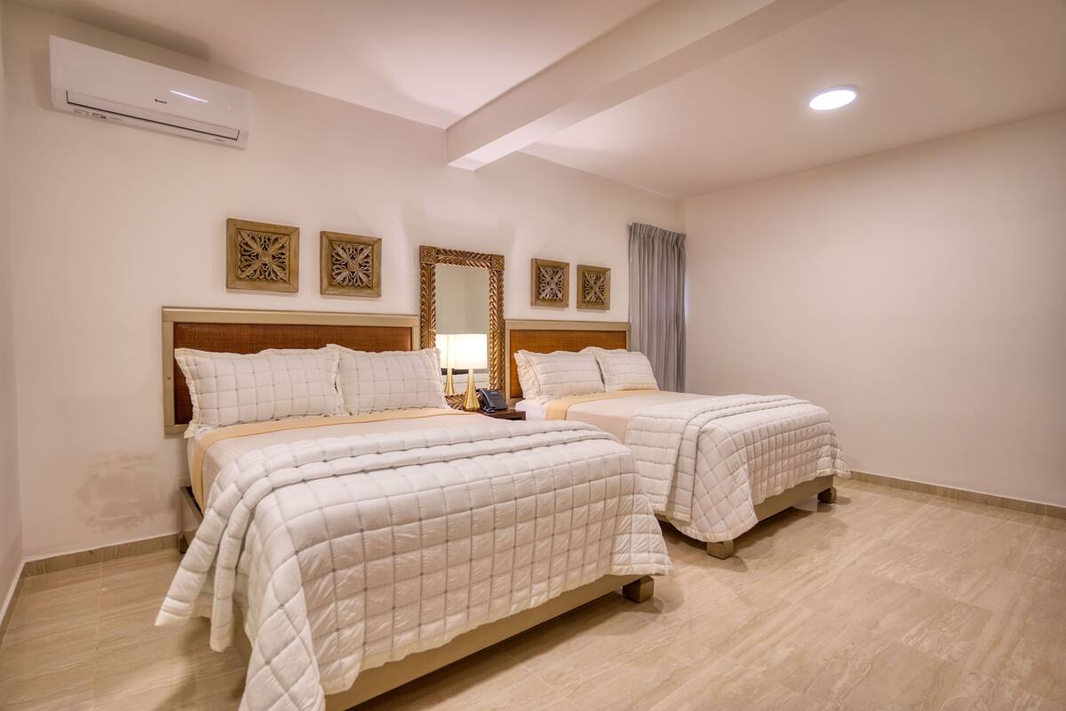 A hotel room with two beds, a large mirror, and decorative wall art.