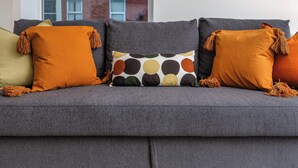 Ein graues Sofa mit vielen Kissen, darunter orangefarbene und gemusterte.