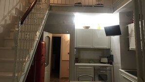 A kitchen with white cabinets, a stove, and a sink. There is a staircase with a railing leading to an upper level. - Lovely apartment Residenze Pessina Naples Historic Center (Napoli)