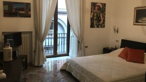 A hotel room with a bed, a TV, a radiator, and a balcony with curtains. - Lovely apartment Residenze Pessina Naples Historic Center (Napoli)