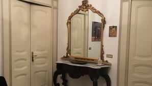 A room with a marble floor, a black ornate table with a mirror, and two white doors. - Lovely apartment Residenze Pessina Naples Historic Center (Napoli)
