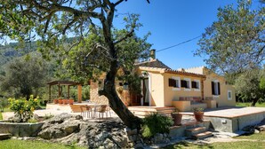 A Mediterranean-style villa with a stone facade, a patio with outdoor furniture, and a view of the surrounding hills. - Busqueroles Petit - Two Bedroom Villa, Sleeps 4 (Pollença)