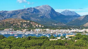 A coastal town with a marina, buildings on hills, and mountains in the background. - Busqueroles Petit - Two Bedroom Villa, Sleeps 4 (Pollença)