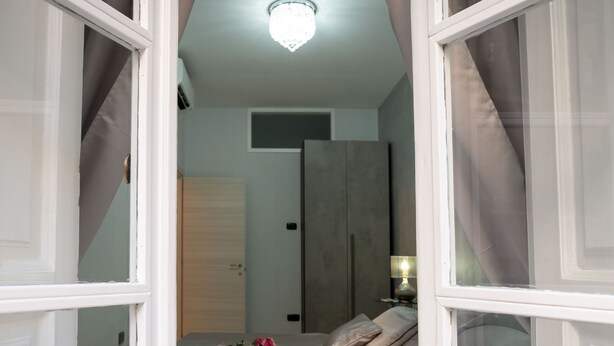 Un dormitorio con cama, cortinas y una lámpara en el techo.