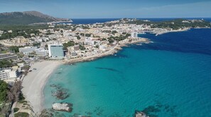 Vista aérea de una ciudad costera con playa, edificios y un faro.