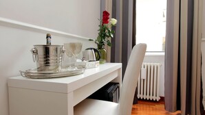 A white desk with a tray, a kettle, a vase with flowers, and a chair.