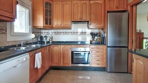A kitchen with wooden cabinets, a stainless steel refrigerator, a Bosch dishwasher, and a tiled backsplash. - Villa TRES PALMERAS piscina con jacuzzi cerca de Benidorm y Albir (l'Alfàs del Pi)