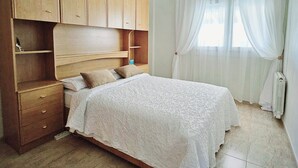 A bedroom with a bed, wooden wardrobe, and a window with curtains. - Villa TRES PALMERAS piscina con jacuzzi cerca de Benidorm y Albir (l'Alfàs del Pi)