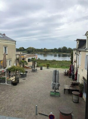 Un cortile con vista sul fiume, arredi esterni e piante in vaso.