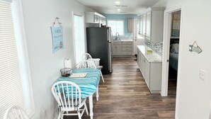 Een moderne keuken met witte kasten, een zwarte koelkast en een houten eettafel met stoelen.