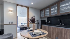 Una cocina moderna con armarios de madera, encimera negra y comedor con mesa y sillas redondas.