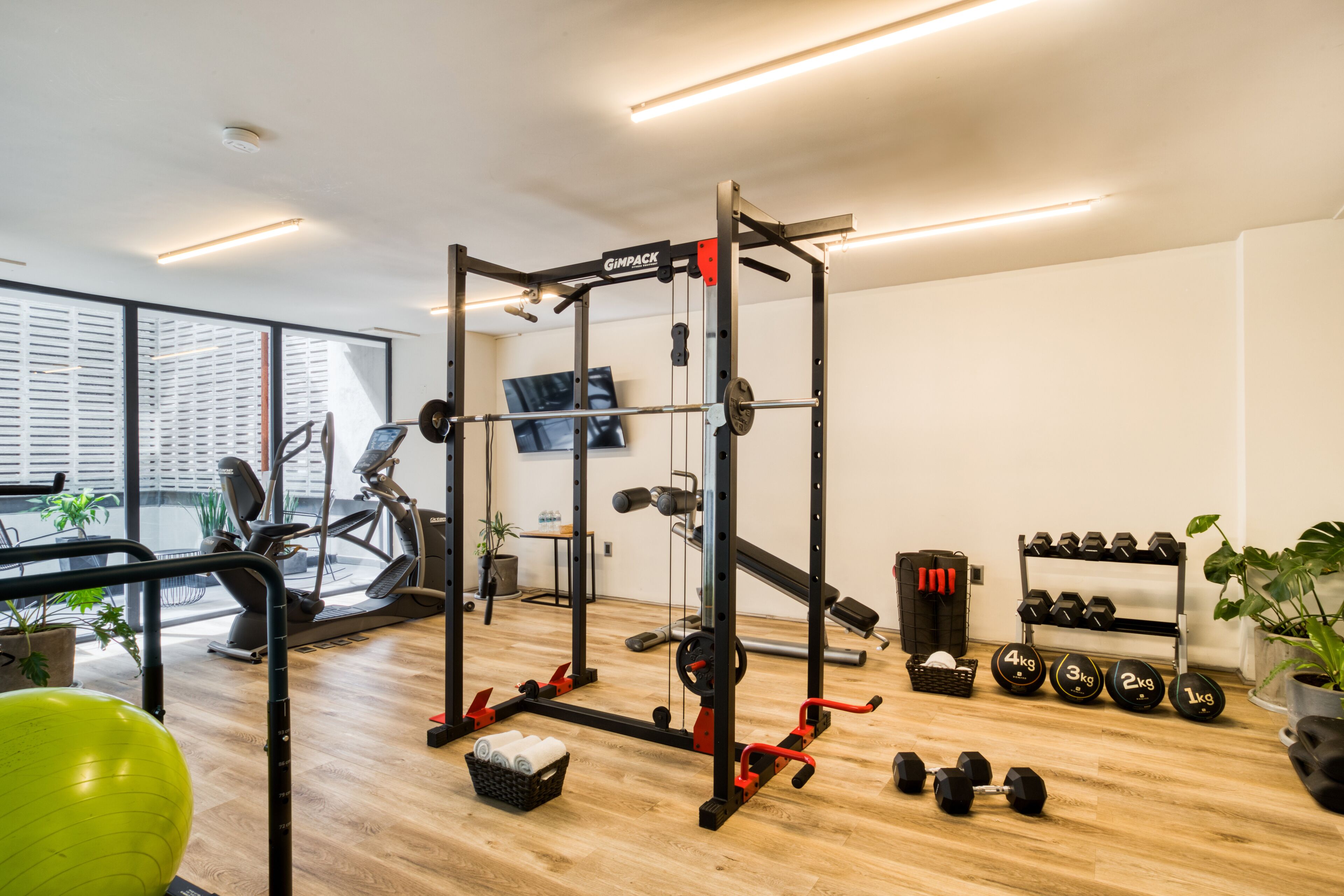 A modern gym with a squat rack, dumbbells, and exercise equipment.