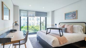 Un dormitorio moderno con una cama grande, un escritorio y vistas a zonas verdes.