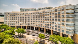 Un edificio moderno con fachada curva, varios pisos y un patio central con árboles.