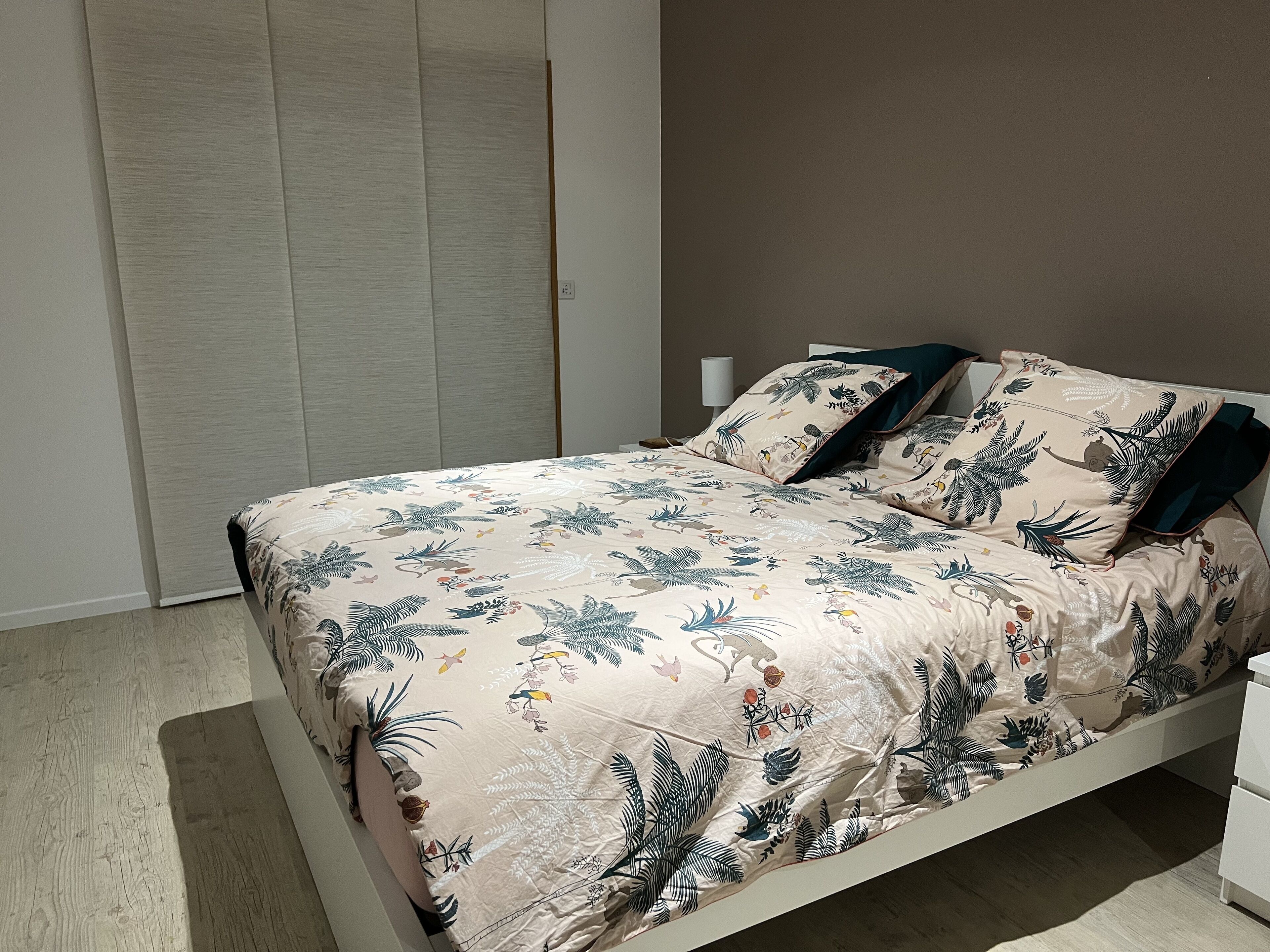Une chambre à coucher avec un lit, des oreillers, une table de chevet et une armoire.