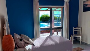 Una camera da letto con due letti, vista su una piscina e una sedia.