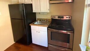 A compact kitchen with a refrigerator, microwave, oven, and dishwasher.