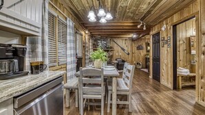 A wooden interior with a dining area, kitchen, and a door leading to another room. - Downtown Creekside Cabin~FirePit~Hot Tub~Game Room (Pigeon Forge)