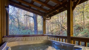 A hot tub with a wooden deck and a view of a forest. - Downtown Creekside Cabin~FirePit~Hot Tub~Game Room (Pigeon Forge)