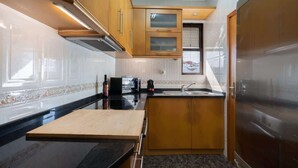 Una cucina compatta con mobili in legno, un piano di lavoro nero e un forno integrato.