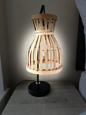 Una lampada in legno con base nera su un comodino.
