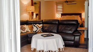 A living room with a leather sofa, a round coffee table, and a ceiling fan.