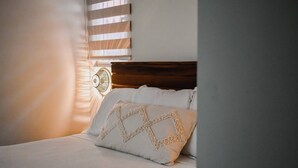 A neatly made bed with a patterned pillow and a wooden headboard.