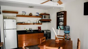 A compact kitchen with wooden cabinets, a microwave, a stove, and a water dispenser.