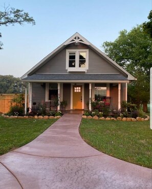 Stunning home with a central entrance, flanked by two windows, set amidst a beautifully manicured lawn.