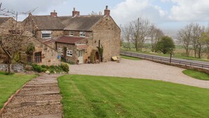 A stone house with a gravel driveway and a wooden pathway leading to the entrance. - The Cottage (Saltburn-by-the-Sea)