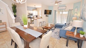 A modern living room with a dining area, a kitchen in the background, and a staircase leading to an upper level. - Vibrant Resort Townhome - south facing and very short walk to amenities (Davenport)