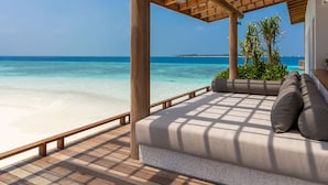 Una terraza de madera con techo de vidrio que da a una playa.