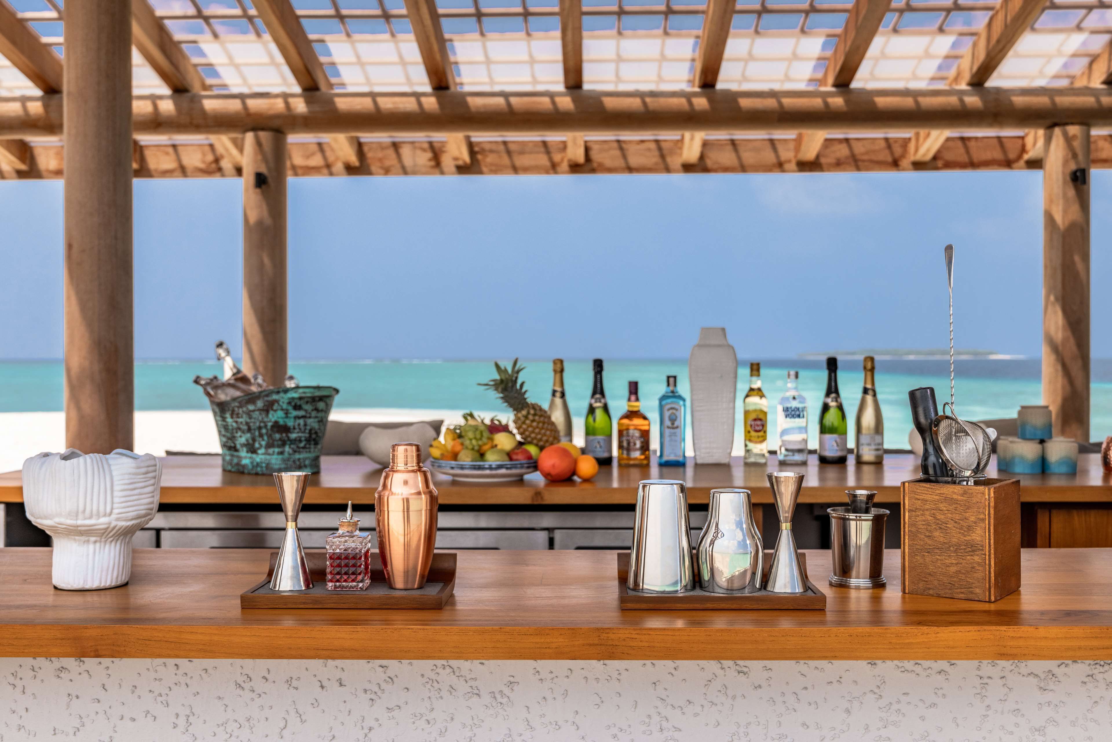 A bar area with a wooden counter, various bar tools, and a fruit bowl.