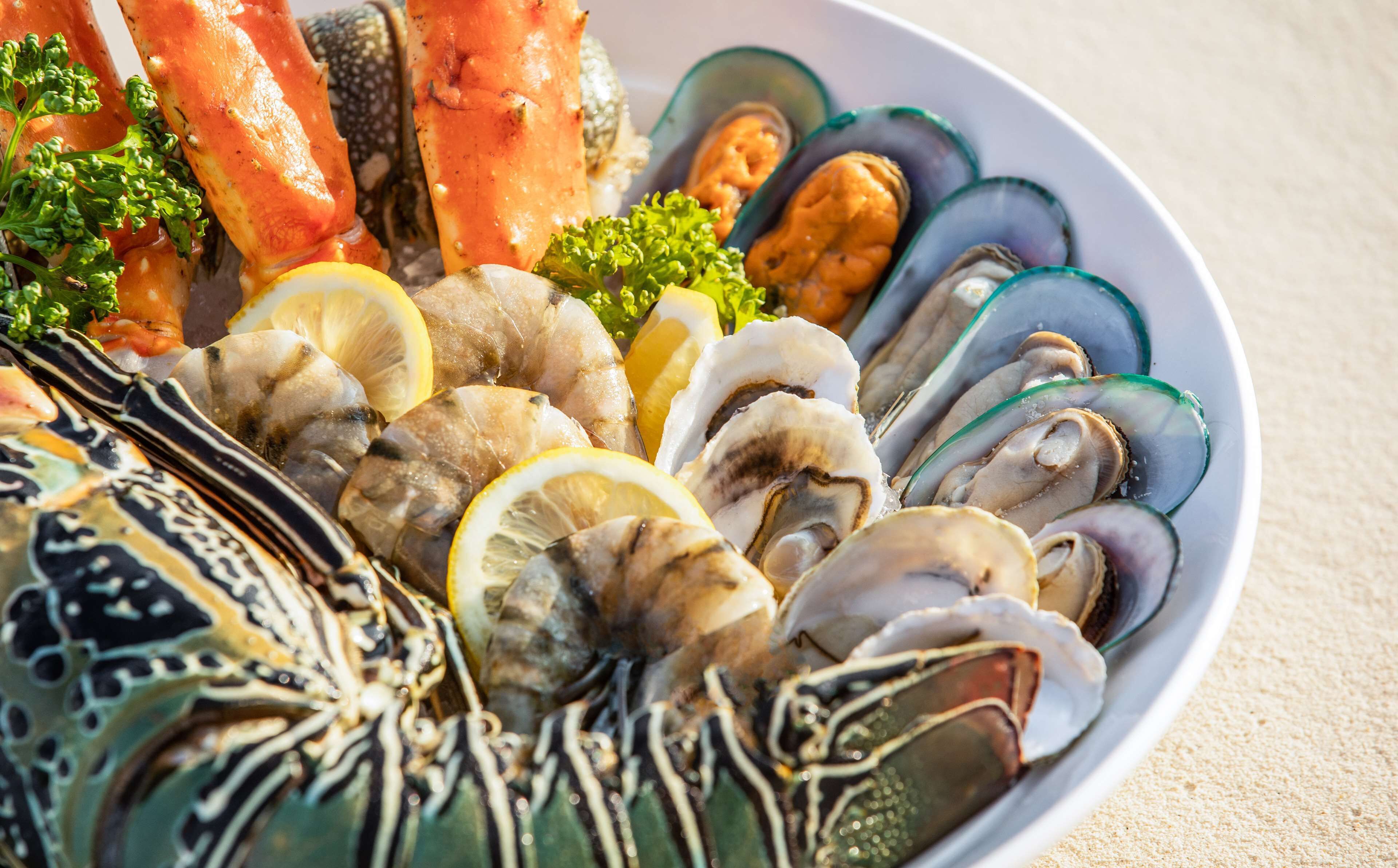 Een visplateau met diverse schelpdieren en zalm, versierd met citroenpartjes en peterselie.