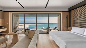 Una habitación de hotel moderna con una cama grande, un sofá, un televisor y un balcón con vistas al océano.
