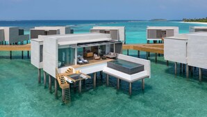 Wasserbungalows mit Glasfassaden, Holzterrassen und Blick auf den Ozean.