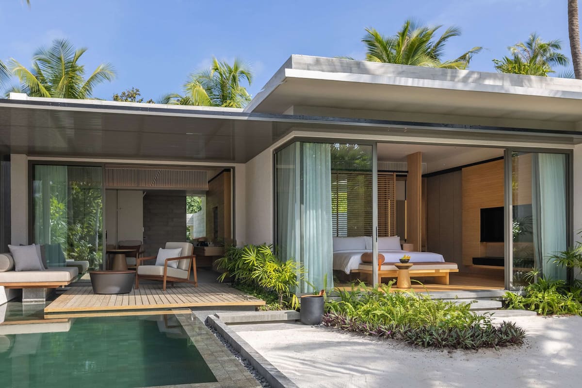 Un espacio exterior moderno con piscina, asientos y un dormitorio con cama y ventana.