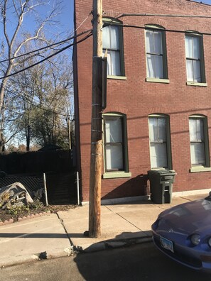 A red brick building with multiple windows, a utility pole, and a parked car. - Second Floor Apartment 1 block from Lafayette Park (St. Louis)