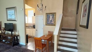 Eine Treppe führt zu einer zweiten Etage, einem Essbereich mit Tisch und Stühlen sowie einem Fernseher im Vordergrund.