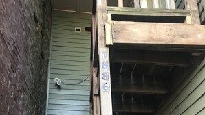 Eine Holztreppe führt zu einer grünen Tür mit einer Nummer.'