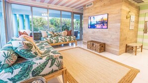 A spacious room with a large bed, a wooden bench, and a television on the wall. - Boutique Suite with Ocean View and Rooftop Pool (Miami Beach)