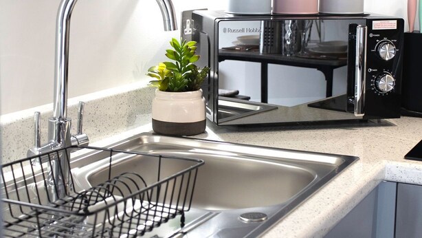 A modern kitchen with a stainless steel sink, a dish rack, and a coffee maker. - Stunning Flat / Walk to town & beach / Bournemouth (Bournemouth)